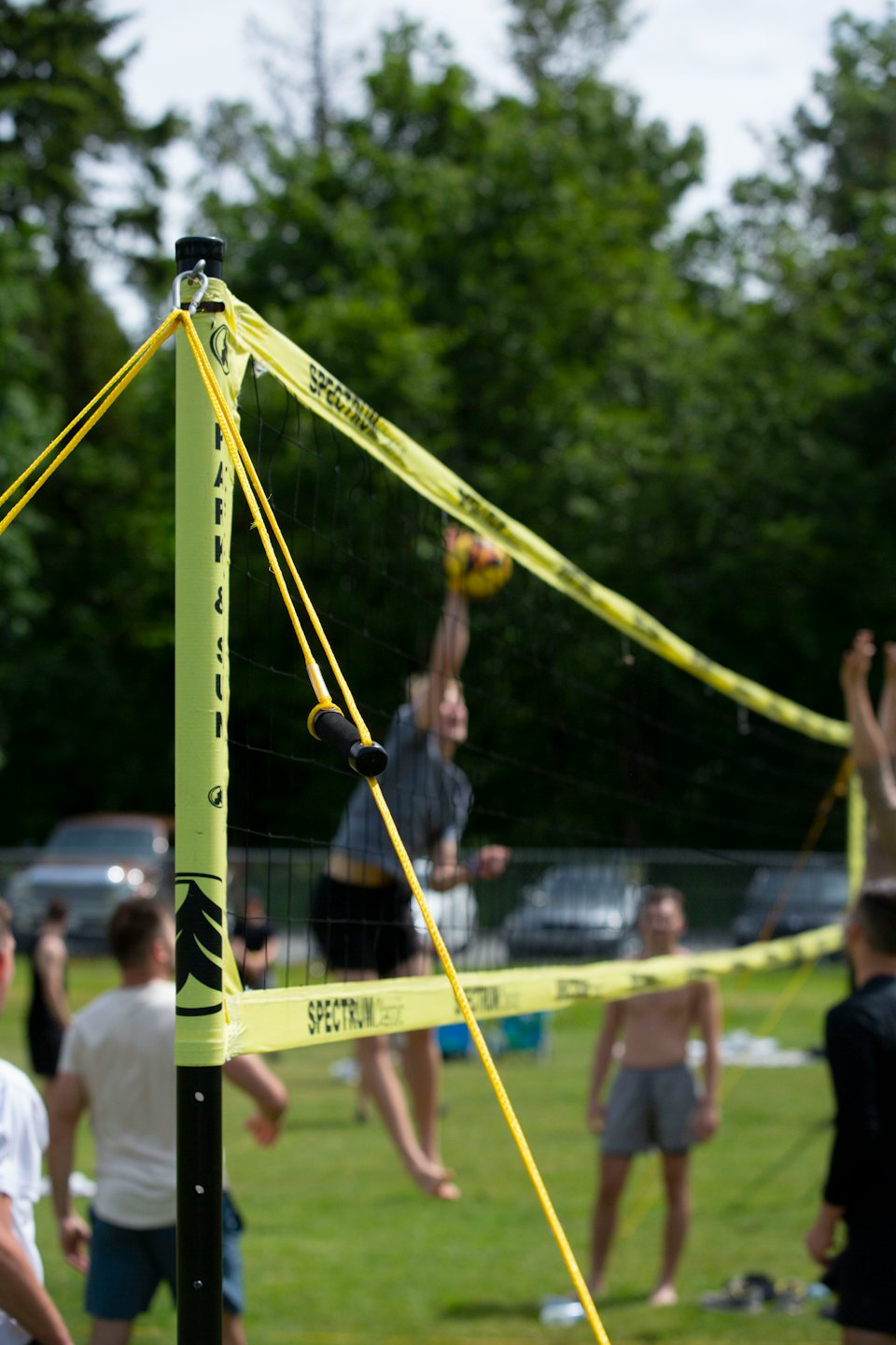 Ein Spieler schmettert einen Volleyball im Freien über das Netz.