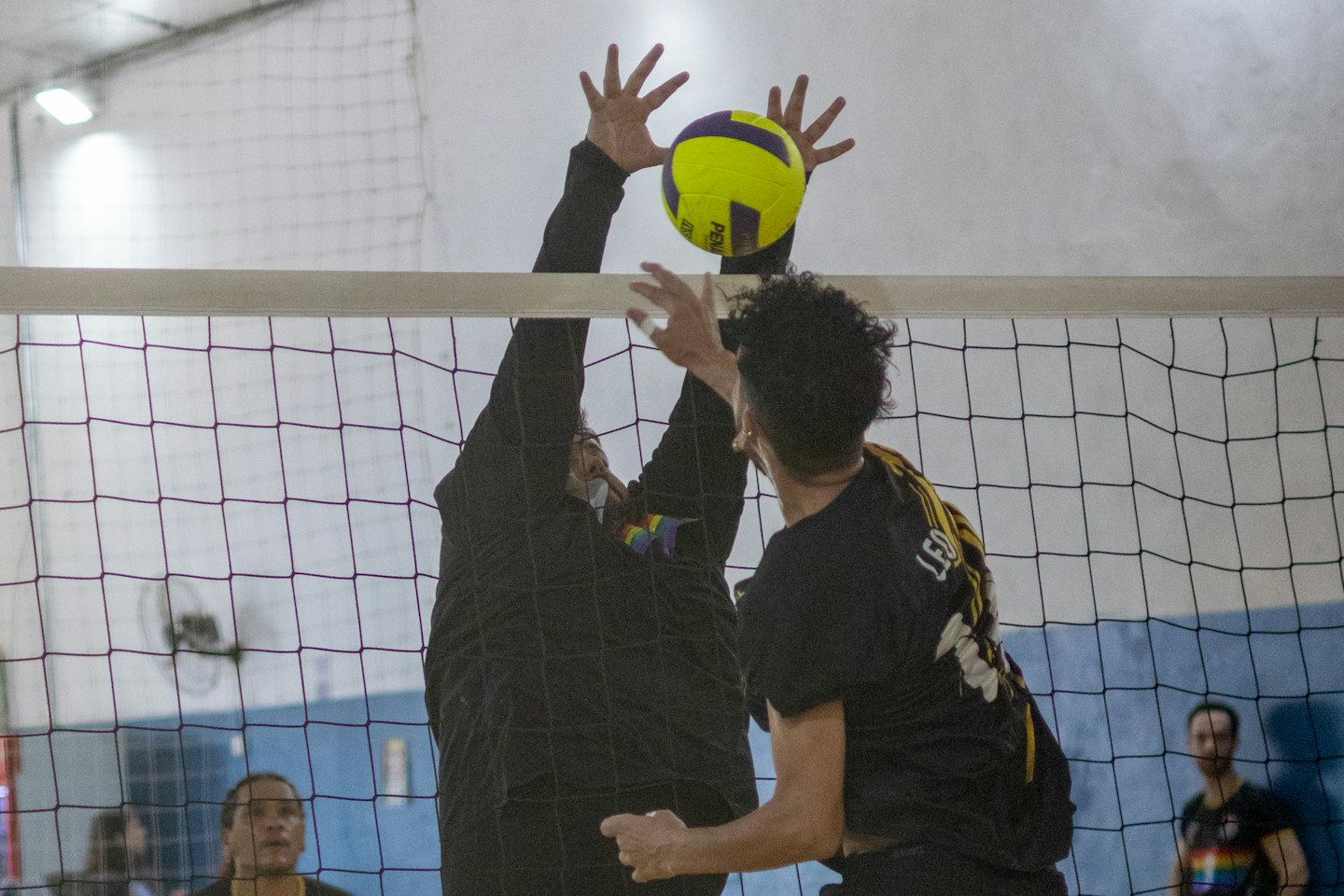 Zwei Volleyballspieler kämpfen am Netz während eines Spiels.