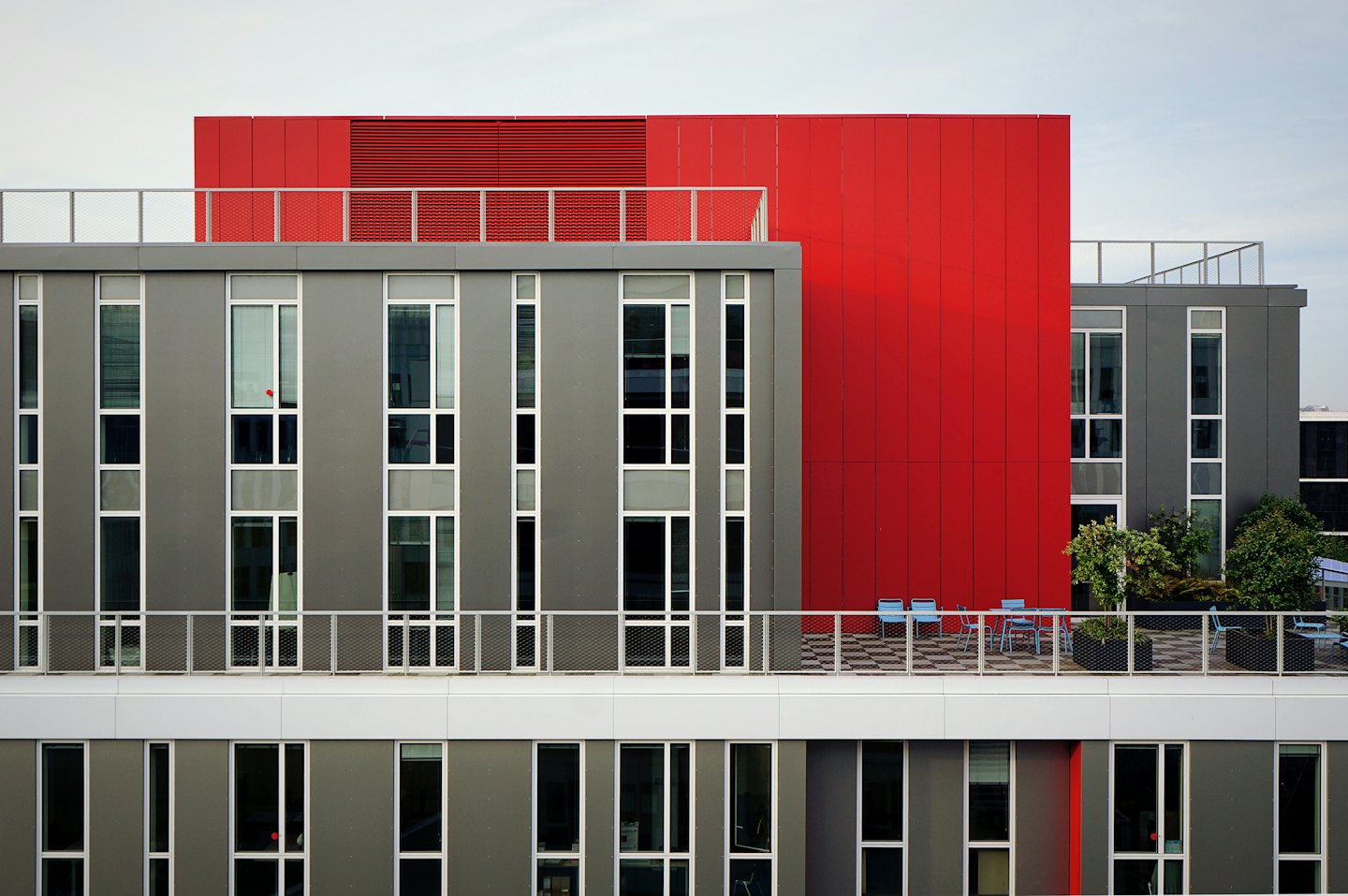 Moderne Gebäudefassade aus rotem Backstein mit Dachterrasse.